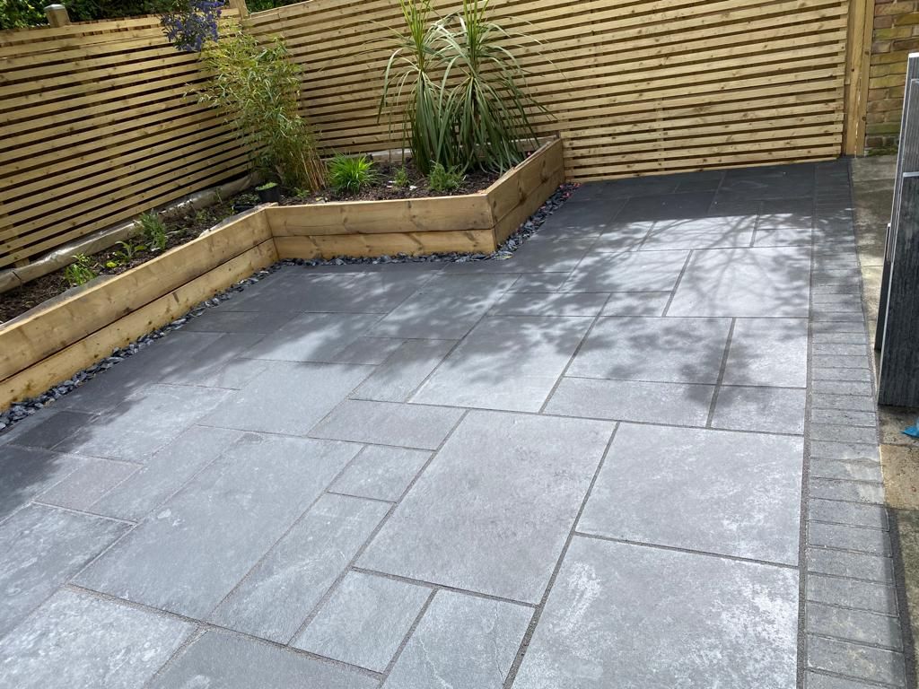 Dark grey porcelain patio with raised railway sleeper planting bed