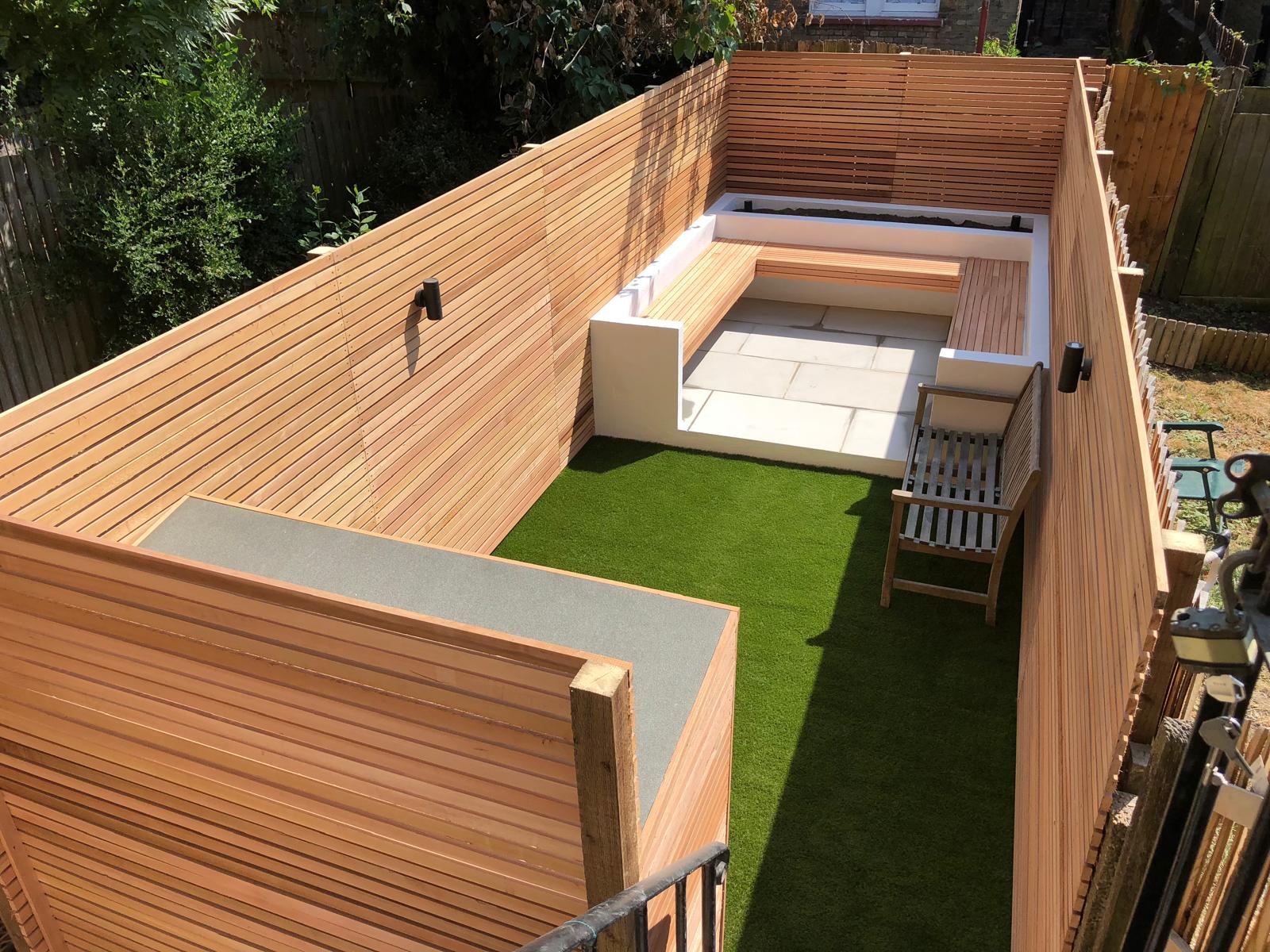 Aerial view of cedar slat fencing, built-in rendered bench, artificial lawn and stone paving